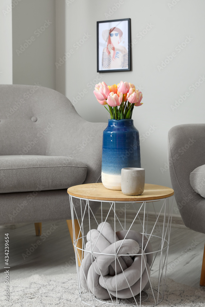 Bouquet of tulip flowers and candle on table in interior of room