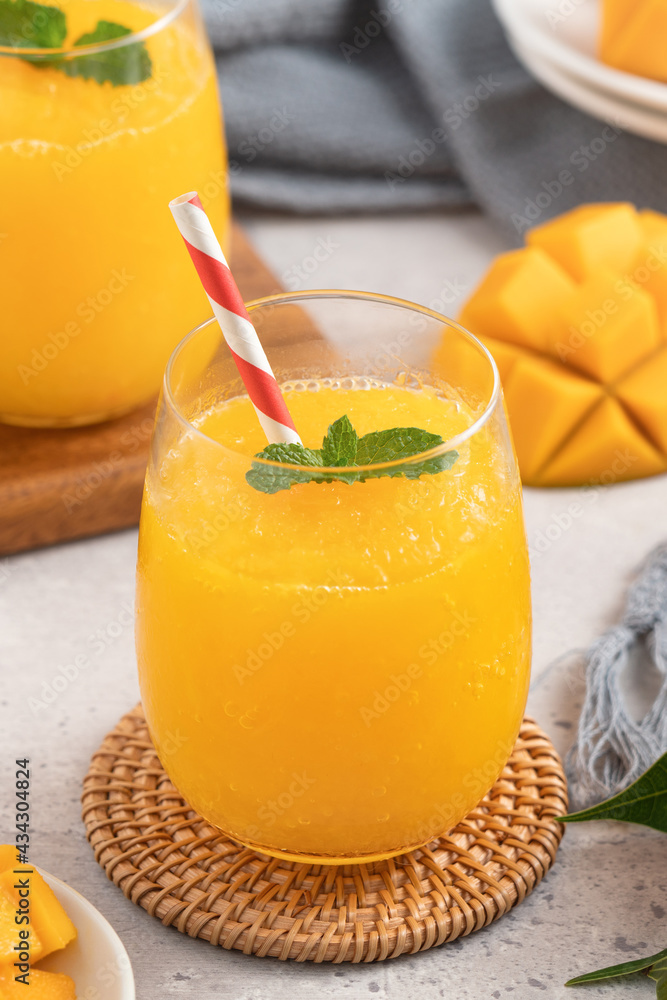 Fresh beautiful delicious mango juice smoothie in a glass cup on gray table background.