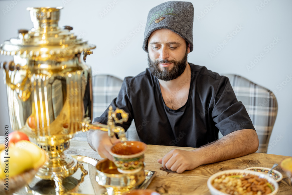 A portrait of the bathhouse attendant in bath hat sitting on the served table in russian style with 