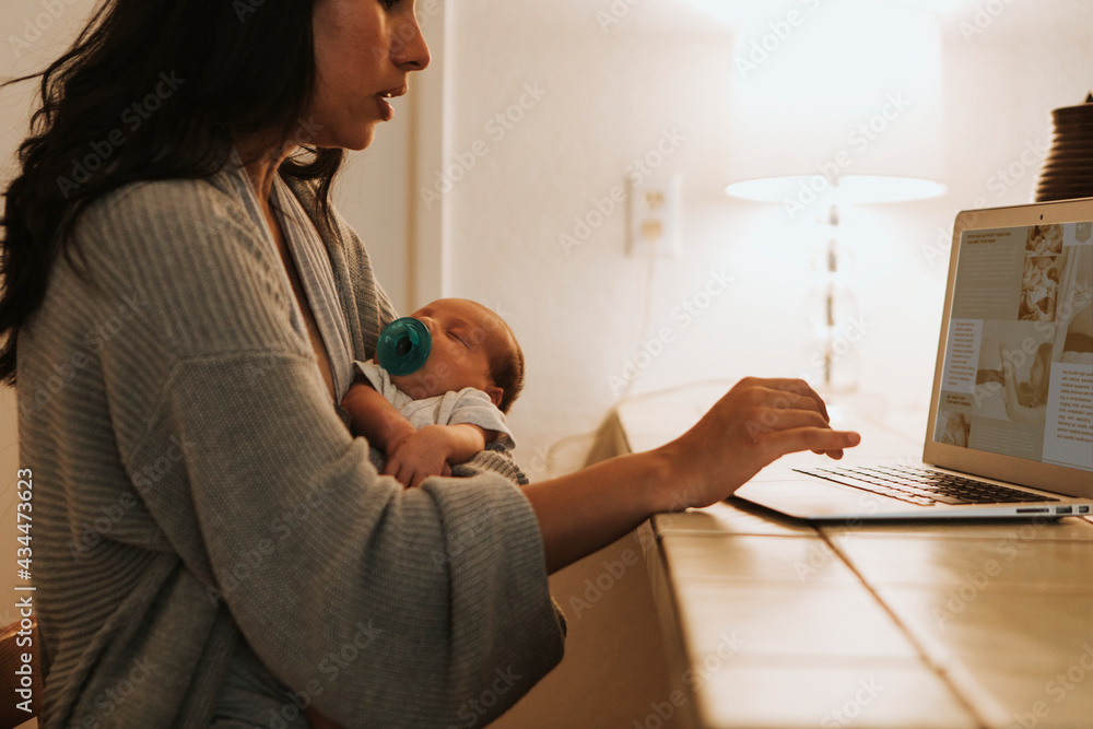 Mother using a computer and holding her baby