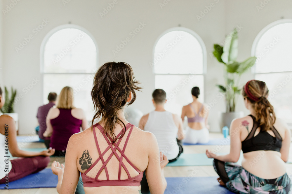 Healthy people doing a Sukhasana yoga pose in a yaga class