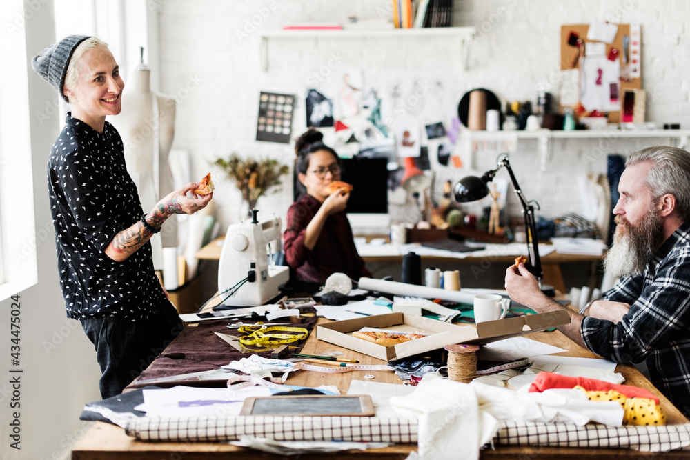 Stylish fashion designers in a workshop eating pizza