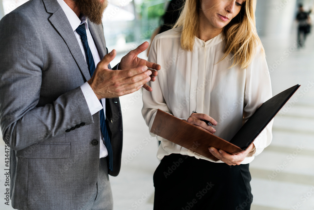 A businessman and a businesswoman having a business talk, writing a business agenda on a notebook