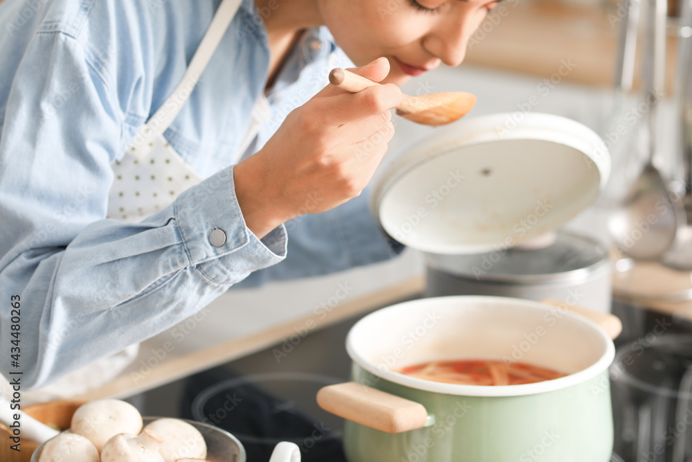 年轻女子在厨房品尝菜肴