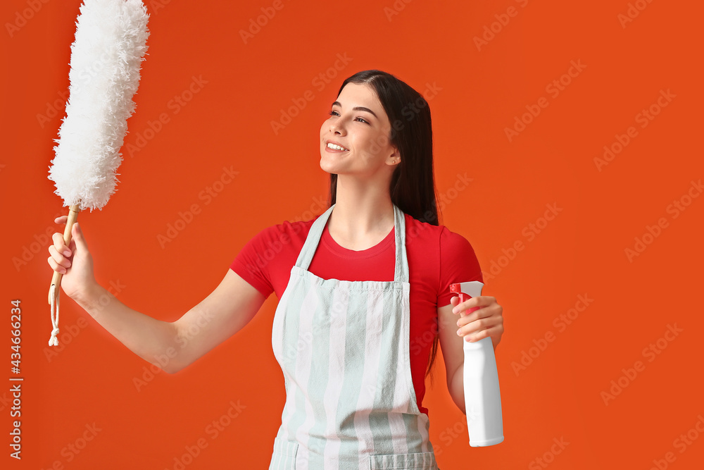 Young woman with dust brush and detergent on color background