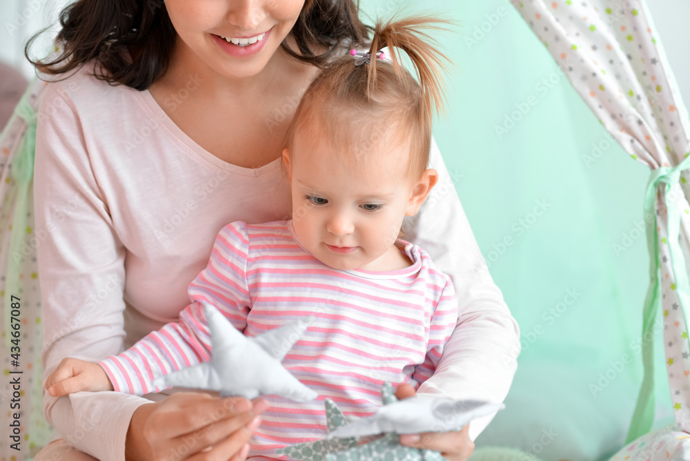 Happy woman and her little daughter playing at home