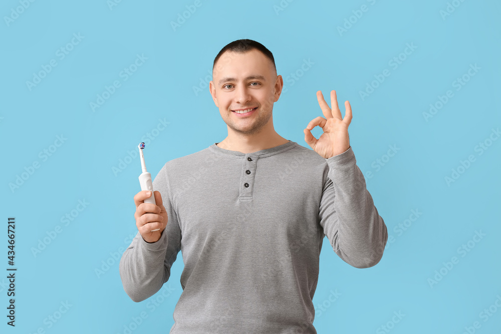 Man with tooth brush showing OK on color background