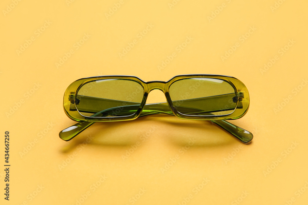 Stylish sunglasses on color background