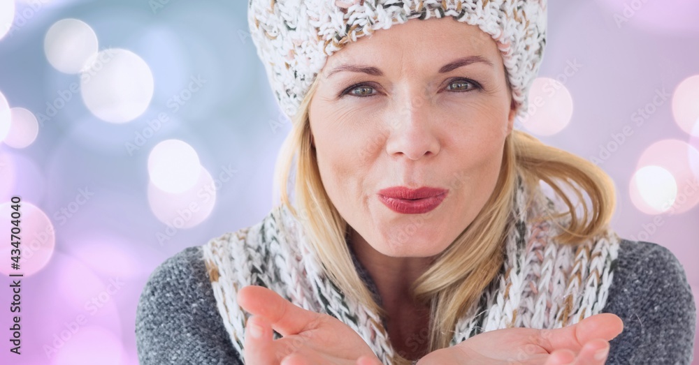 Portrait of caucasian woman blowing a kiss against spots of bokeh lights in background