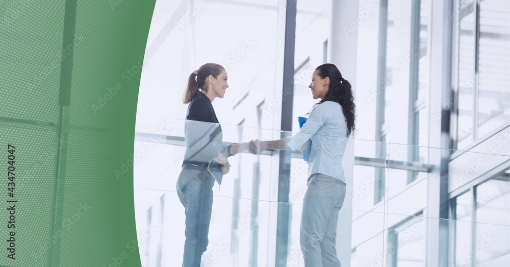 Abstract technology background against two businesswomen shaking hands at office