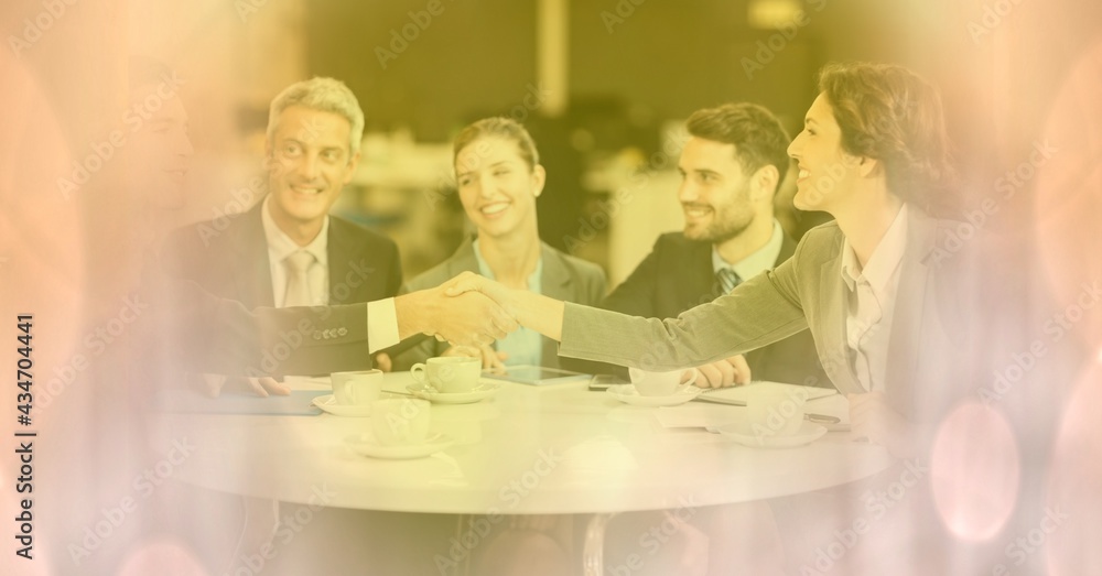 Composition of businessman and businesswoman handshake with glowing pink spots of light