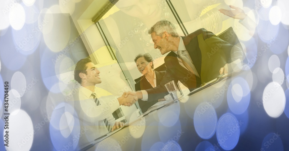 Composition of businessman handshake with glowing blue spots of light