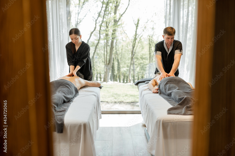 Two masseurs doing a deep back massage to guests with pampering technique. Wellness and leisure time