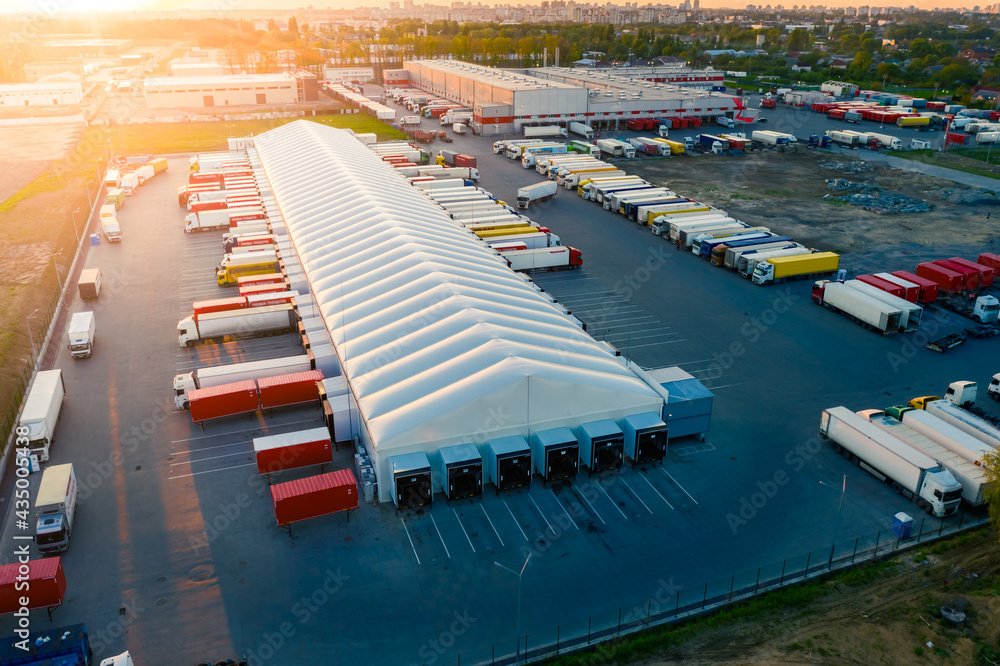 Logistics park with warehouse and loading hub. Semi-trailers trucks stand at ramps and wait for load