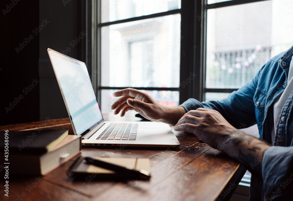 Close-up of male hands with laptop. Man is working remotely at home. Freelancer at work