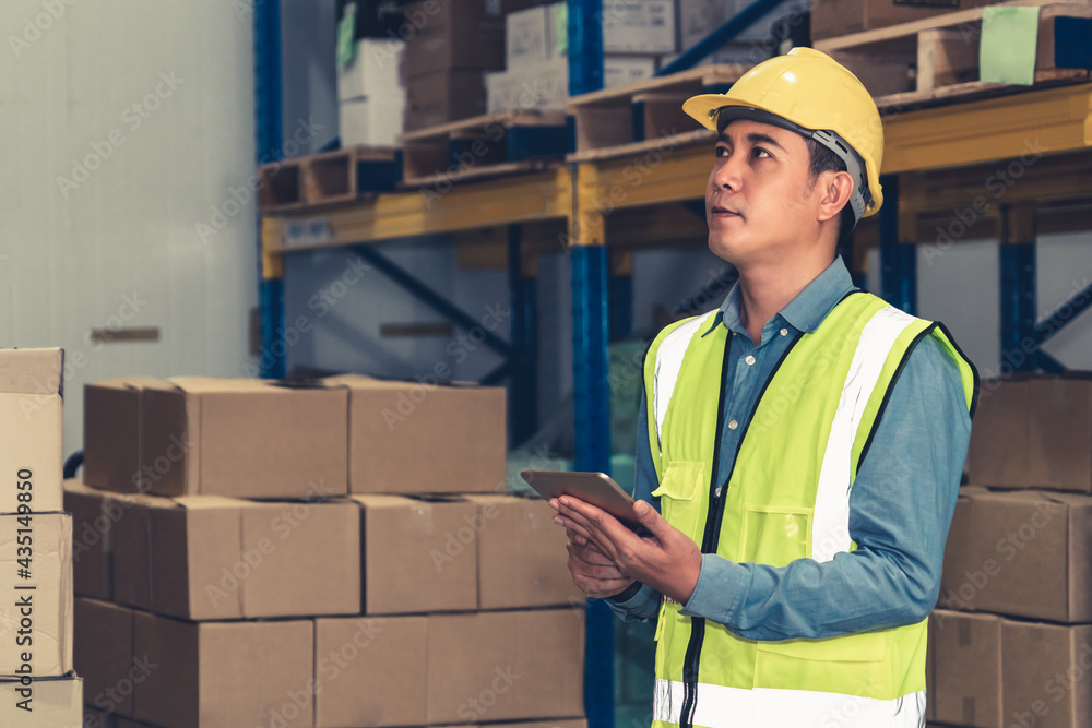 Asian warehouse worker checking packages in storehouse . Logistics , supply chain and warehouse busi