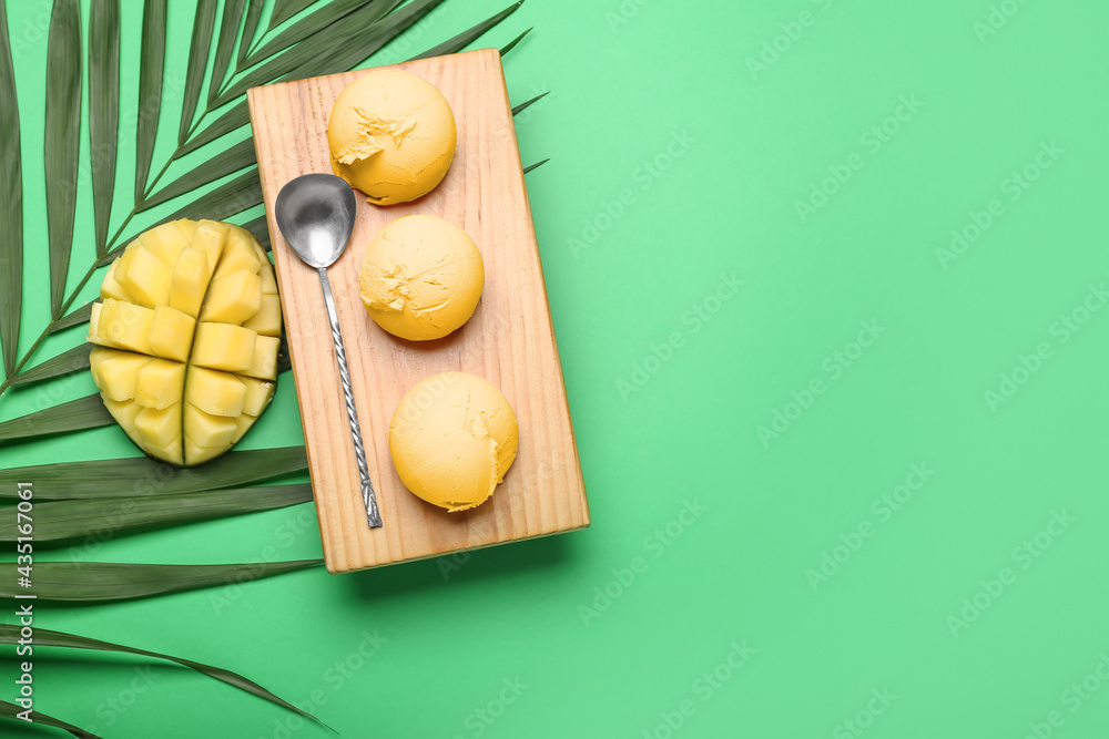 Tray with tasty mango ice cream and palm leaf on color background