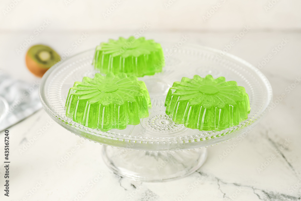 Dessert stand with tasty kiwi jelly on light background