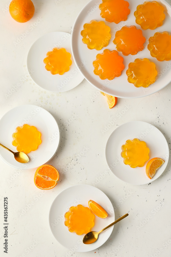 Plates with tasty orange jelly on white background