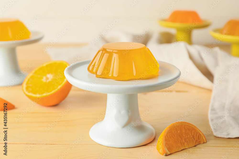 Dessert stand with tasty orange jelly on light wooden background