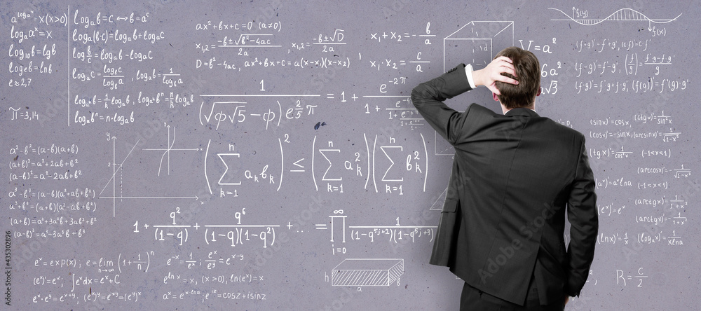 Self-education concept with back view on man in black suit in front of college blackboard with mathe