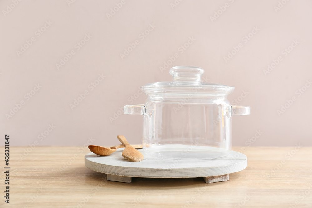 Stylish cooking pot and spoons on light wooden background