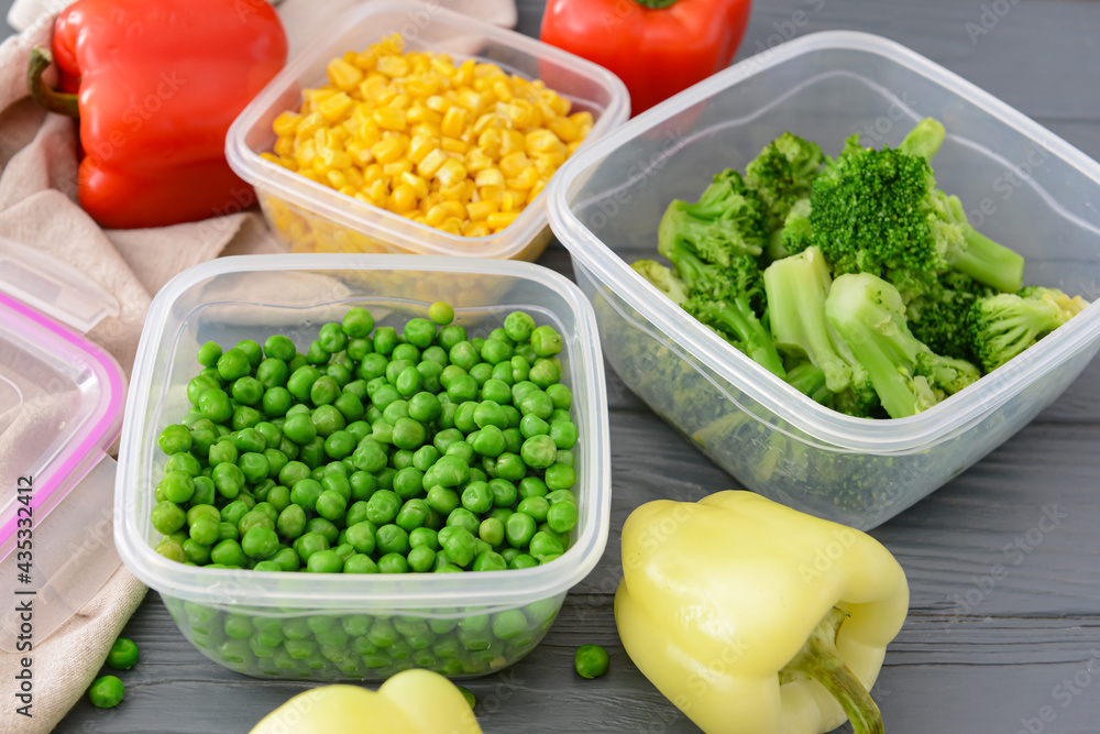 Plastic containers with vegetables on dark wooden background