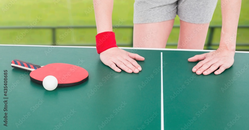 Composition of mid section of female table tennis player leaning on table with ball and racket