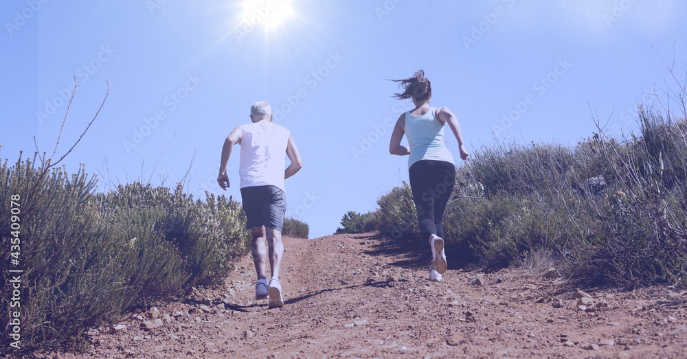 Composition of rear view of man and woman running in countryside