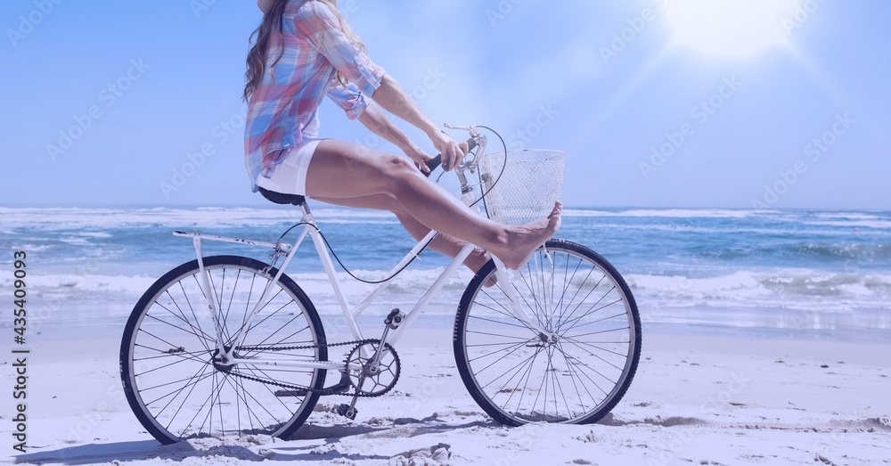 Composition of woman riding bike on beach with copy space