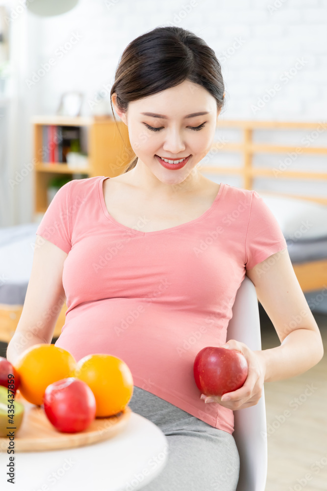 Asian pregnant woman holding apple