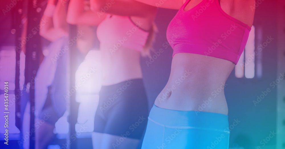 Composition of group of fit women exercising over light blur