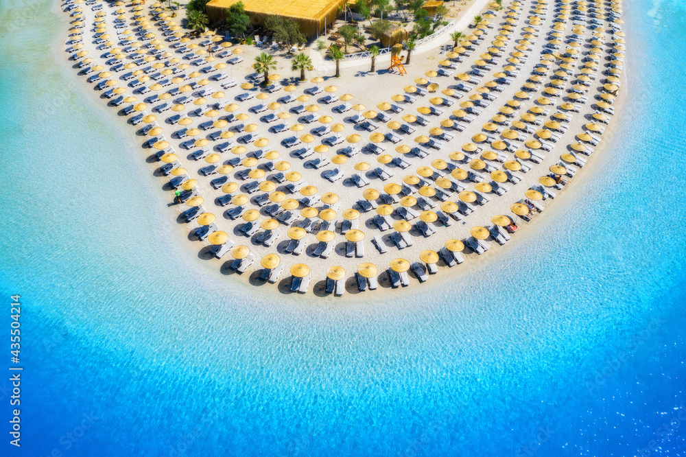 Aerial view of sea, empty sandy beach with sunbeds and umbrellas at sunny day in summer. Blue lagoon