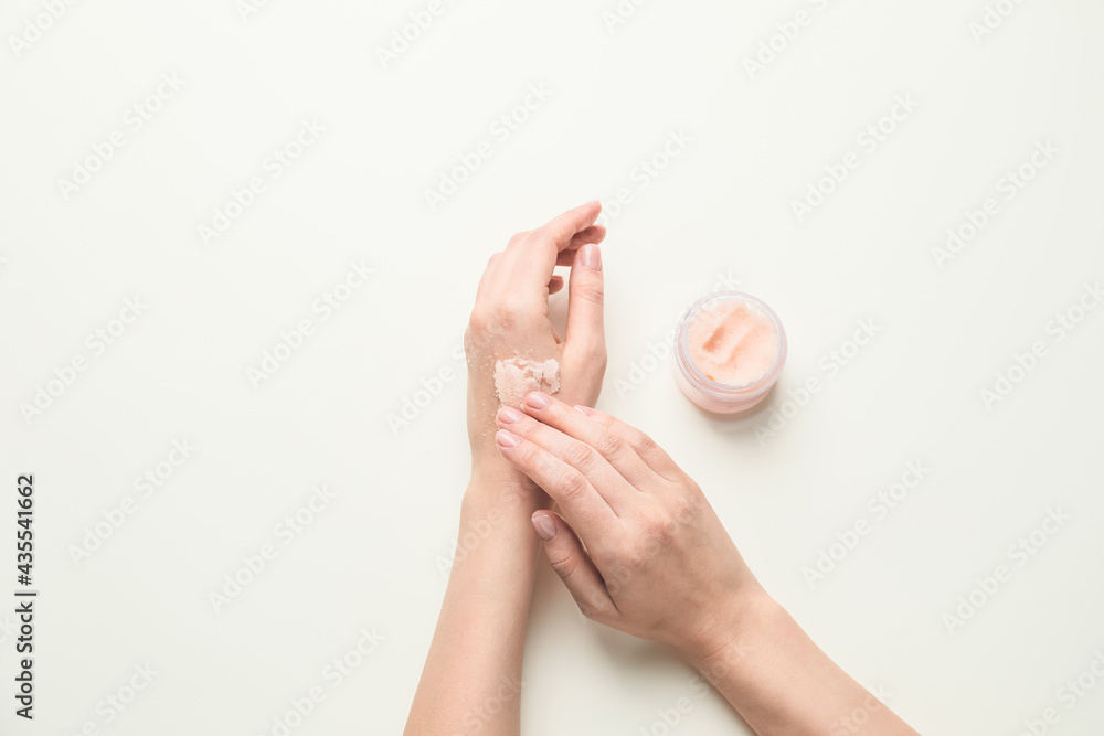 Female hands with body scrub on light background