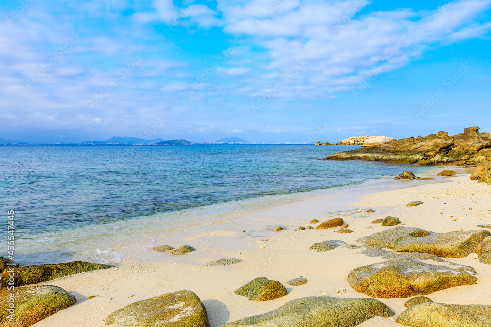 海滩、大海和蓝天上美丽的云朵的景观。海滩上的岩石。