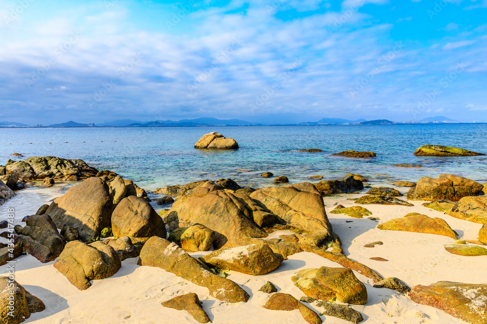 海滩、大海和蓝天上美丽的云朵的景观。海滩上的岩石。