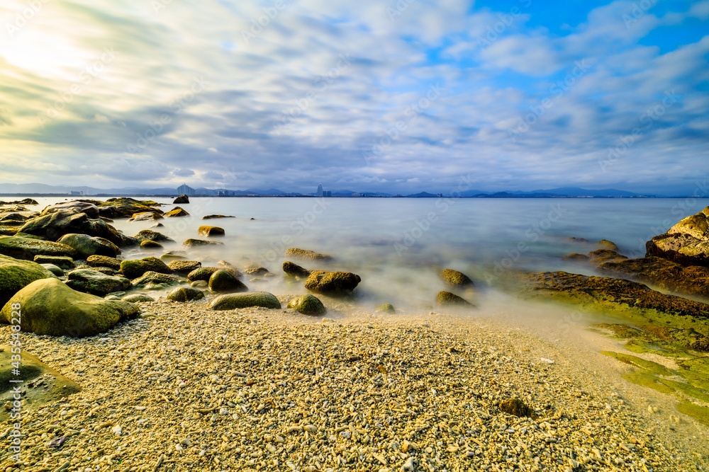 海滩、大海和蓝天上美丽的云朵的景观。海滩上的岩石。