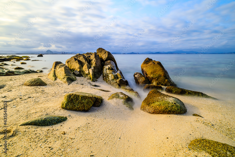 海滩、大海和蓝天上美丽的云朵的景观。海滩上的岩石。