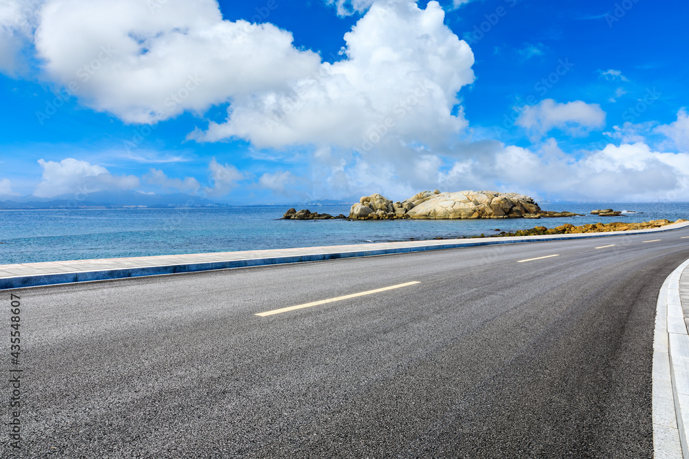 Asphalt road and beautiful seaside scenery under blue sky.