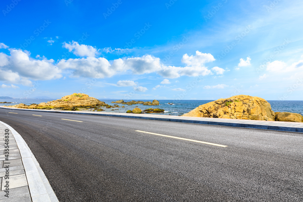 Asphalt road and beautiful seaside scenery under blue sky.