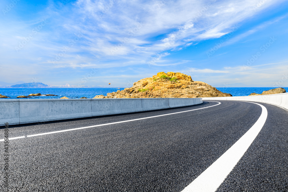 Asphalt road and beautiful seaside scenery under blue sky.