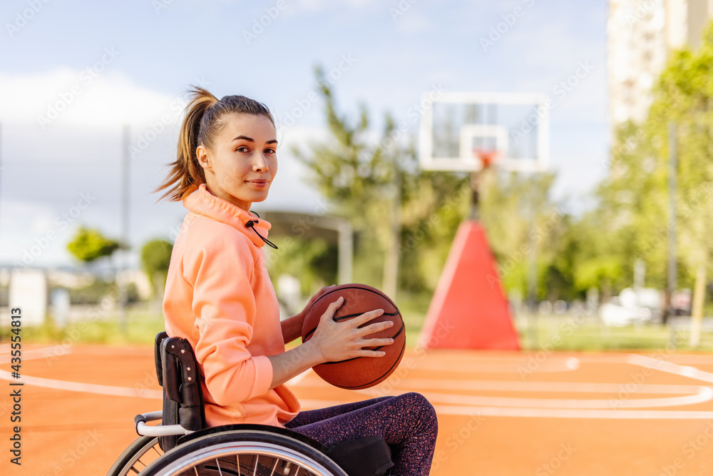 Disabled girl, looking at camera, holding basket ball.