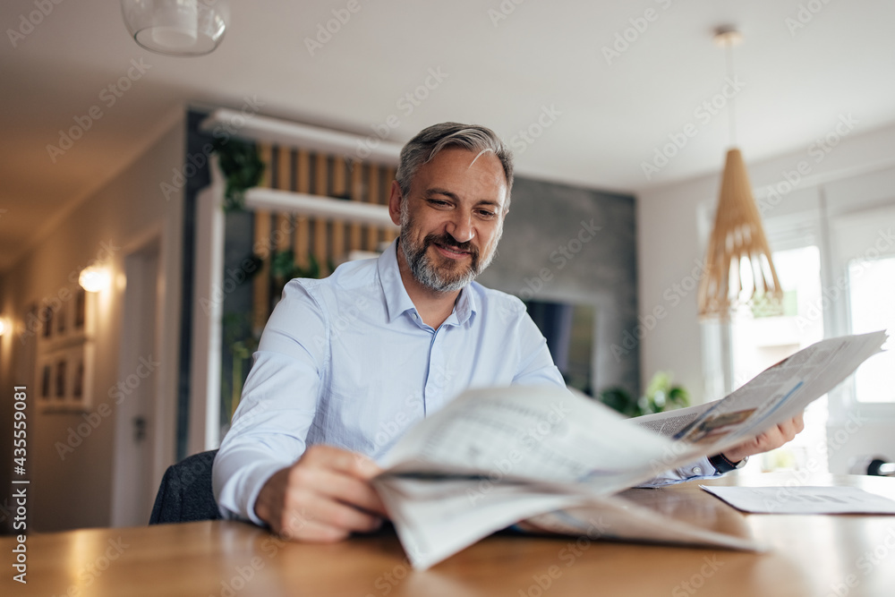 Adult man reading todays newspaper before coffee.