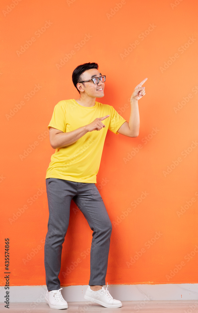 Full body photo of Asian man in yellow shirt on orange background