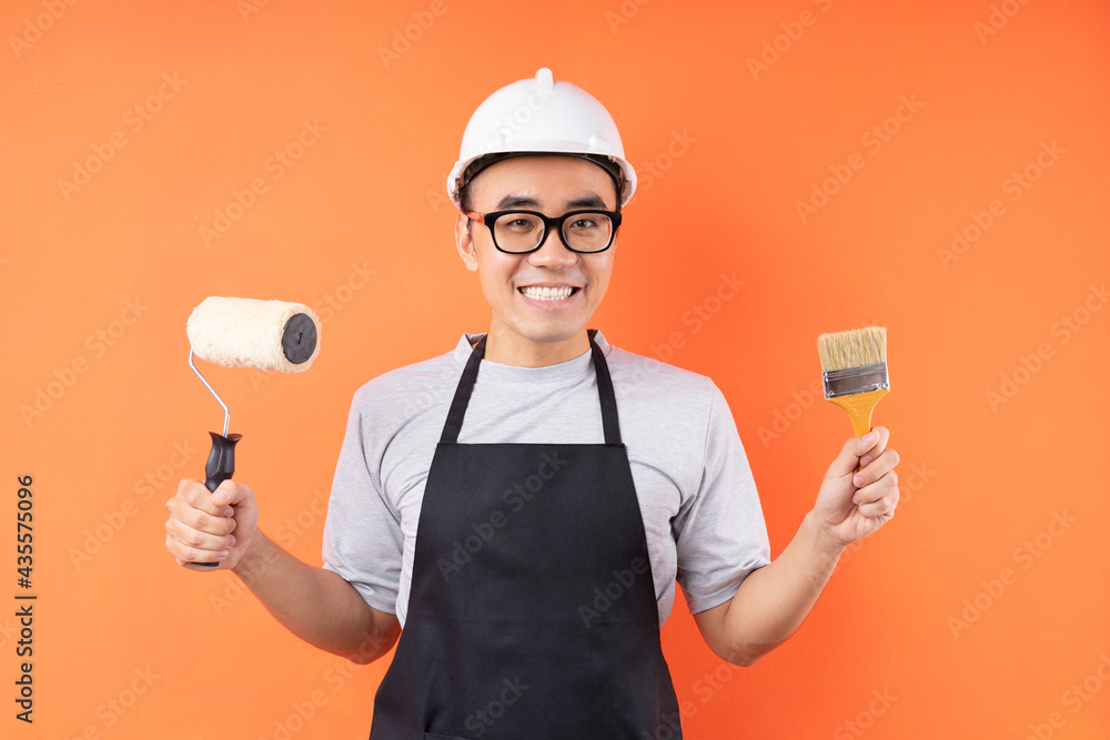 Asian painter holding paint brush posing on orange background