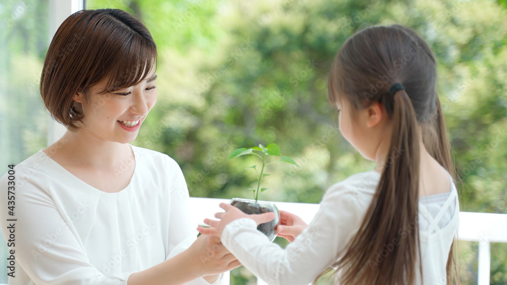 観葉植物を持つ娘と母