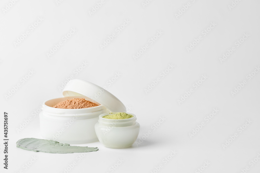 Jars with cosmetic clay on white background