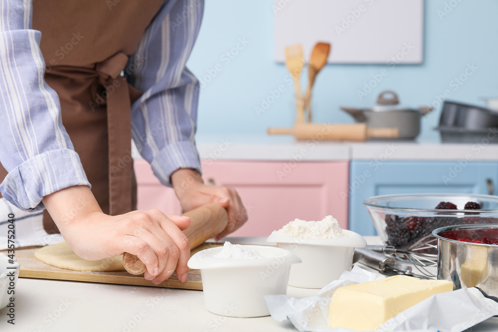 Woman making dough on board in kitchen