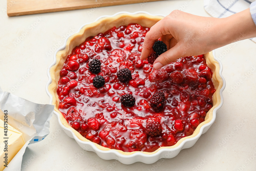 Woman cooking berry pie in kitchen