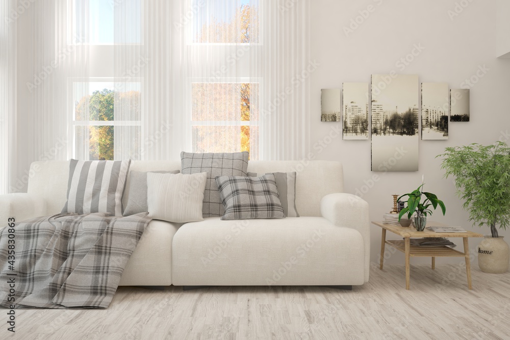 Stylish room in white color with sofa and autumn landscape in window. Scandinavian interior design. 